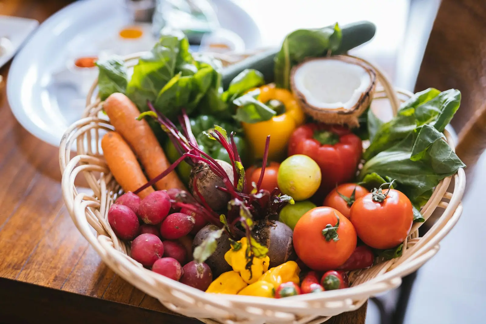 Panier en osier rempli de légumes frais : tomates, carottes, radis, poivrons